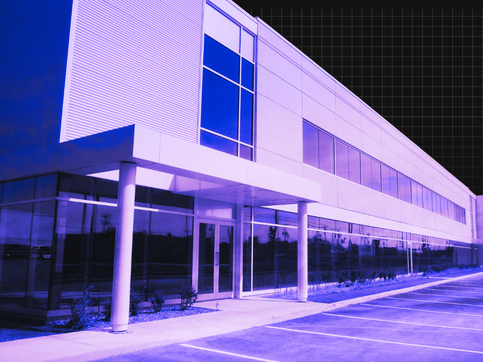 Purple-tinted office building with glass windows, geometric design, and grid pattern; empty parking lot in foreground.