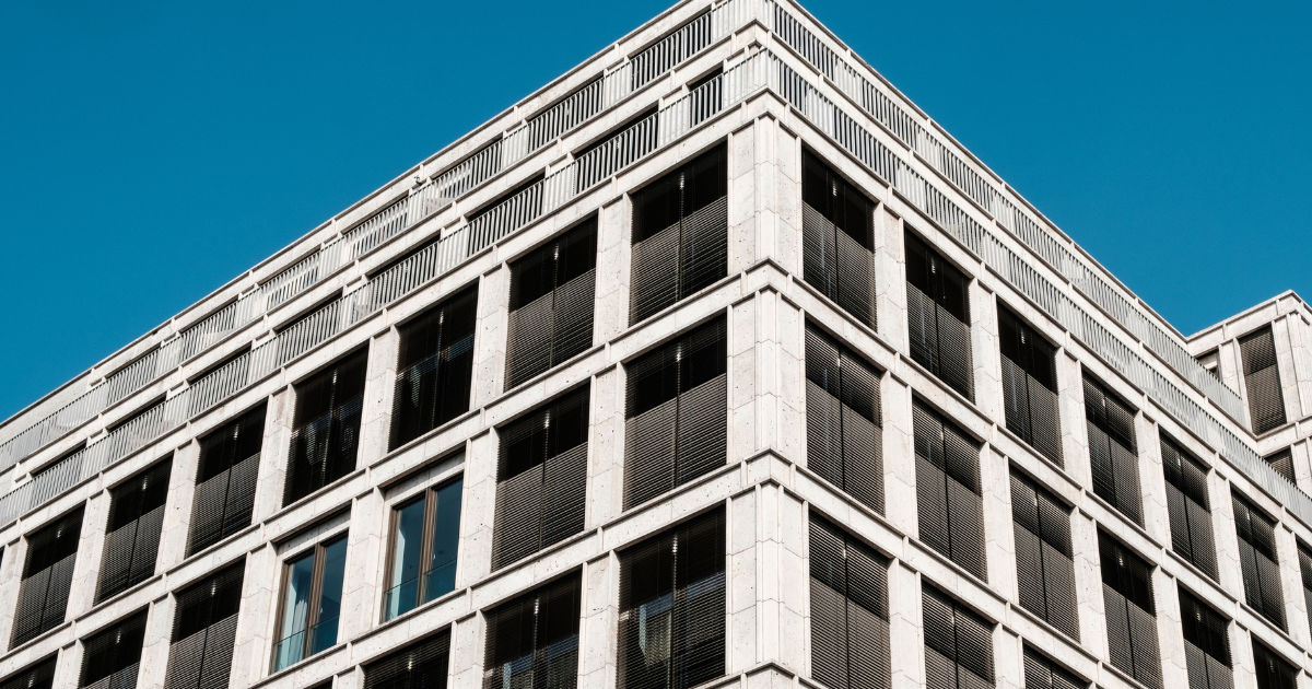 Modern building corner with grid-like black and white panels against a clear blue sky, illustrating an article on office building defaults.