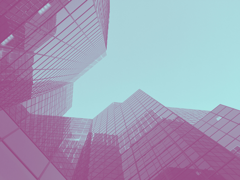 Modern glass skyscrapers with pink tint reflecting each other against a clear blue sky, emphasizing urban architectural aesthetics.