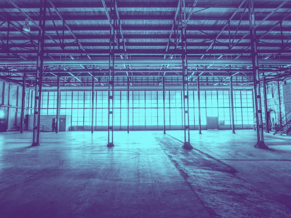 Empty warehouse with high ceilings, concrete floor, and frosted windows for natural light; featured in SoCal industrial leasing article.