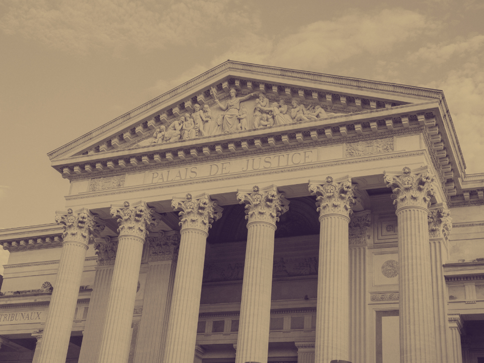 Sepia image of a courthouse with Corinthian columns and sculptures, marked "PALAIS DE JUSTICE." Featured on a real estate site.