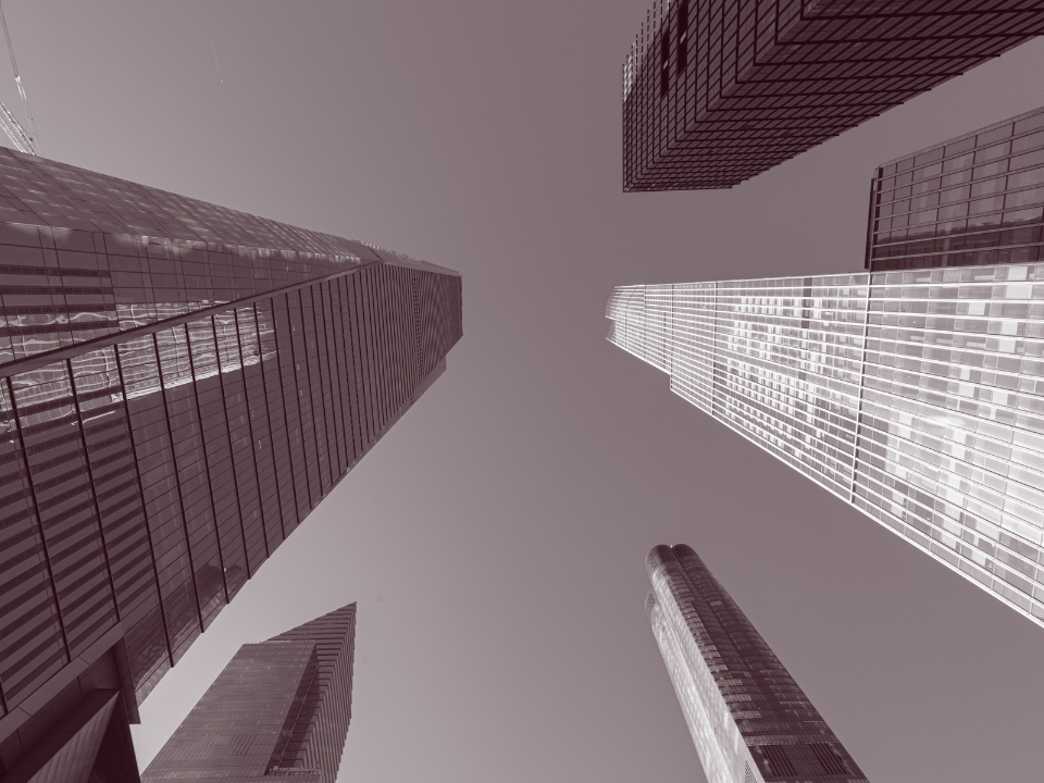 View of modern skyscrapers with glass facades, converging toward the sky, highlighting height and design.