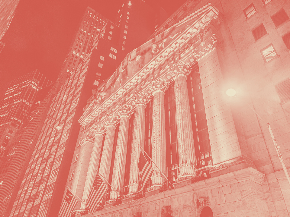 A red-tinted image of a classic building with columns and American flags, surrounded by skyscrapers, for a real estate article.