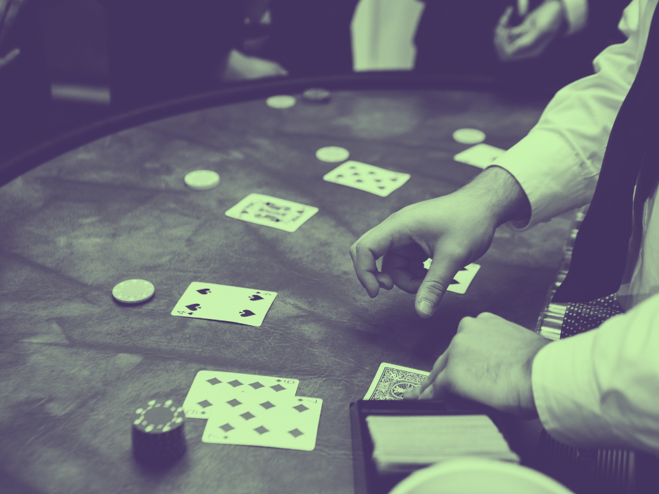 Dealer shuffles cards at a poker table with chips and players in the background. Image for article on Bally's $940M Chicago Casino financing.