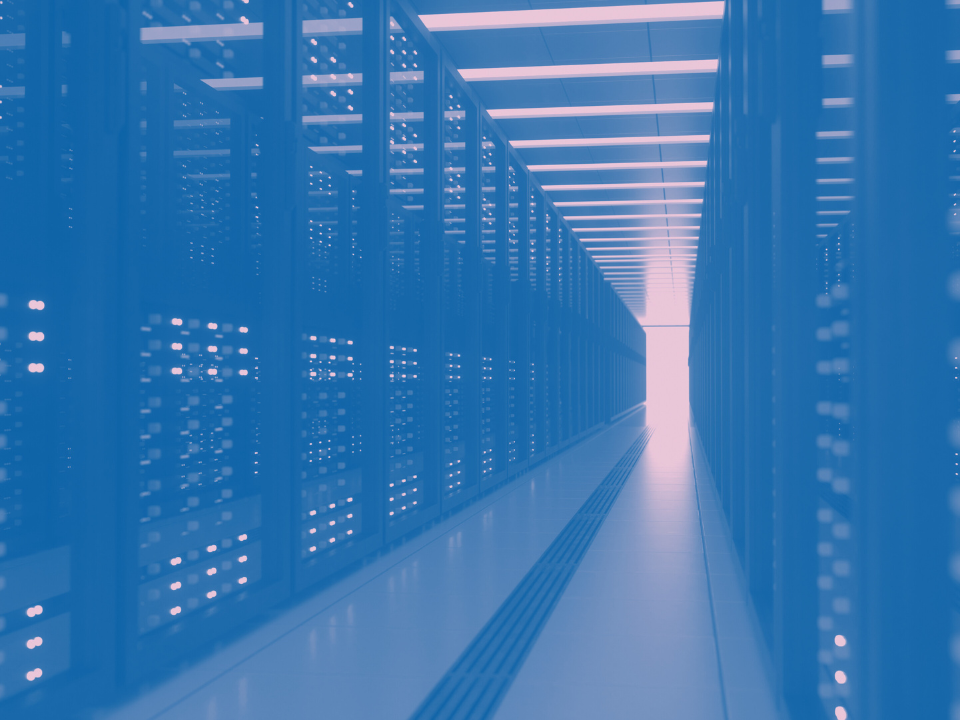 A narrow aisle in a dimly lit data center, lined with tall server racks. Bright vanishing point in the distance.