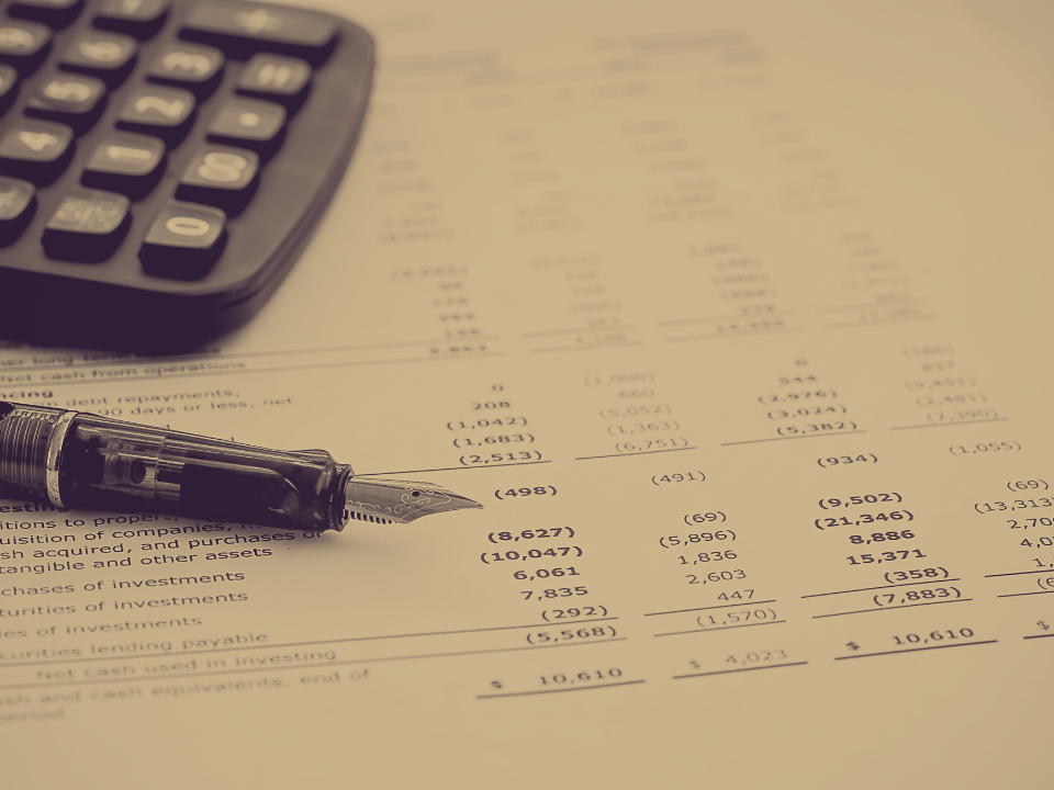 A sepia-toned image of a fountain pen on financial data, with a calculator visible, for an article on real estate fraud.