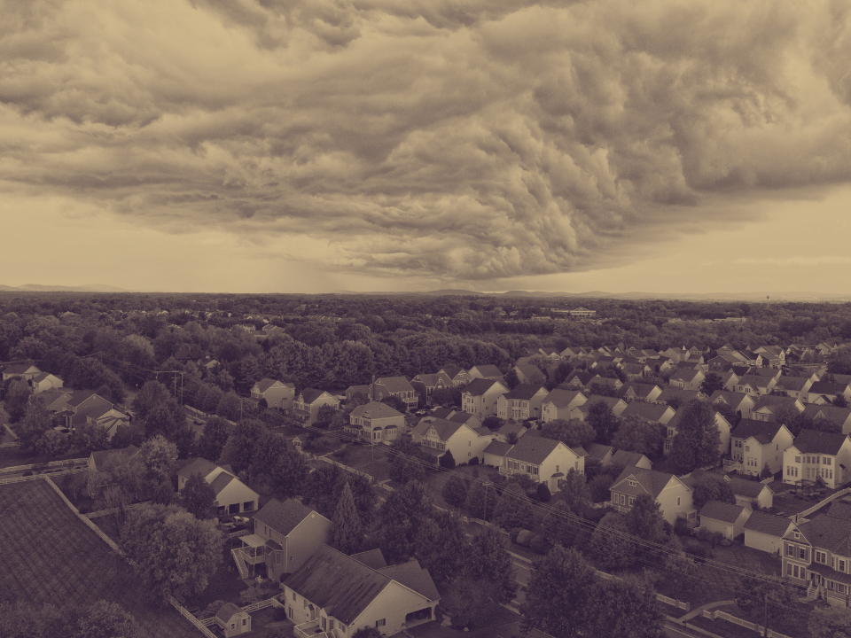 Aerial view of residential neighborhood under swirling storm clouds, for a real estate article on Hines' 1.2K units in N. Virginia.