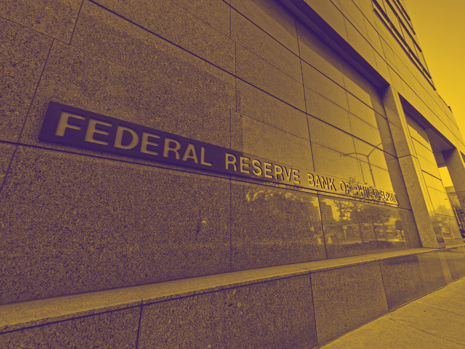 Federal Reserve Bank of Minneapolis facade with stone wall sign. Image has a warm tint, for real estate article on rate cut hopes.