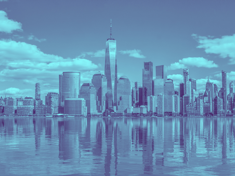 City skyline with skyscrapers and tower reflecting on water under blue-tinted sky. Image for article: Manhattan Renters Bidding Wars.