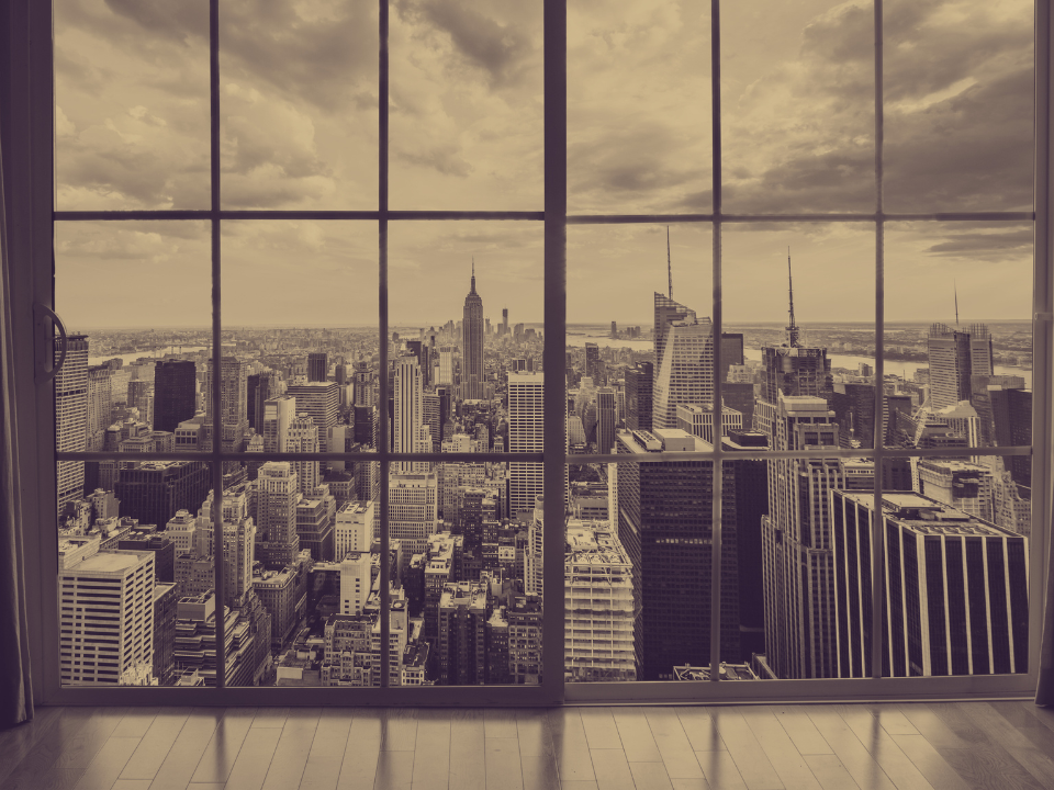 City skyline view through large windows; skyscrapers under cloudy sky with sepia tone. For article on NYC hotel union clash.