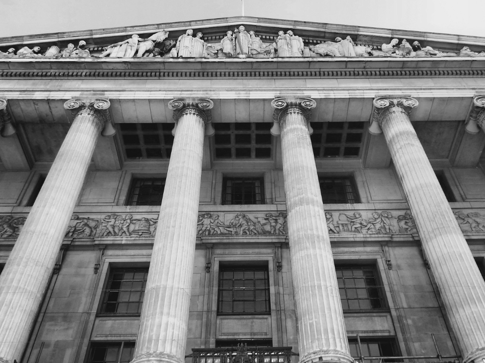 Black and white neoclassical building facade with columns and sculptures; featured in a real estate article on commercial stress.