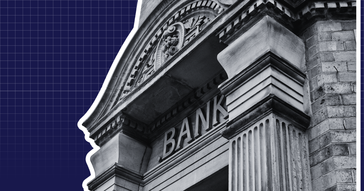 B&W image of a bank facade with columns on dark blue grid; "BANK" partially visible. For real estate article on CRE loans.
